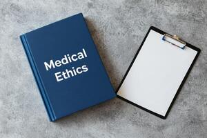 Medical ethics book beside a clipboard on a textured surface. photo