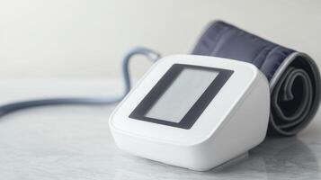 Digital blood pressure monitor with cuff on a light background, symbolizing health and wellness. photo