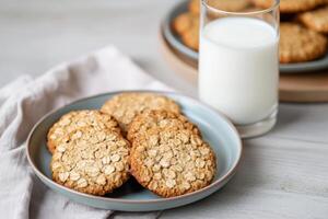 Delicious oatmeal cookies served with a glass of milk on a rustic table. photo