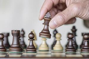 Hand moving a wooden chess piece during a strategic game on a chessboard. photo
