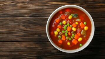 Colorful vegetable soup in a white bowl on a rustic wooden table. photo