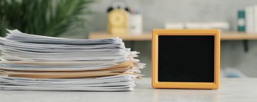 Stack of documents beside a chalkboard in a modern workspace. photo