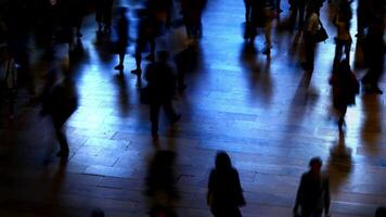 The atmosphere is heavy in the dimly lit station with rushing commuters in the evening video
