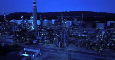 A sprawling industrial refinery complex seen at nighttime emitting a distinctive blue glow video