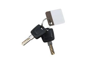 A set of two car keys with black plastic heads attached to a metal keyring, accompanied by a blank white and brown key tag, isolated on a white back photo