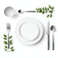 A minimalist dining setup featuring a white plate, utensils, and a cup, beautifully adorned with fresh green leaves, perfect for showcasing modern culinary design. photo