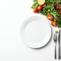 A fresh, vibrant salad featuring leafy greens, ripe tomatoes, and sliced lemon arranged around a blank white plate, ready for a healthy meal or culinary presentation. photo