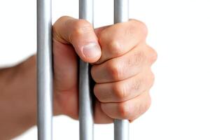 A close-up of a human hand gripping prison bars, symbolizing confinement and the struggles related to justice and freedom photo