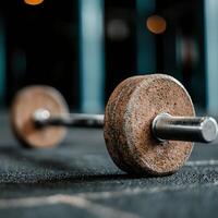 A close-up shot of a rusted dumbbell resting on a gym floor. The image captures the essence of weightlifting and fitness, perfect for sports and exercise enthusiasts. photo