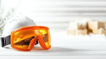 Safety gear including a white helmet and orange goggles is displayed against a soft background, showcasing protection for sports or leisure activities in a winter setting. photo