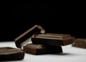 Stack of Dark Chocolate Squares on a Dark Background Close-Up shot photo