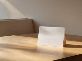 A white card on a wooden table in front of a window photo