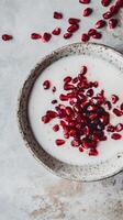 Coconut milk topped with fresh pomegranate seeds in a rustic bowl on a neutral background photo