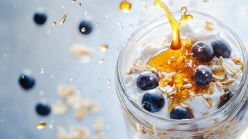 Delicious layered yogurt with blueberries and honey splashing in a jar during a bright morning photo