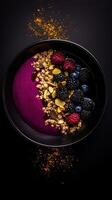 Healthy bowl of mixed berries, granola, and almond flakes served in a black dish against a dark background for breakfast or snack photo