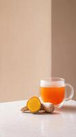 Delightful turmeric and ginger tea served in a transparent cup on a light surface photo