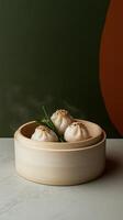 Bamboo basket filled with freshly made dumplings on a minimalist table with a green wall in the background photo