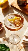 Crystal-clear coupe glass filled with a refreshing cocktail garnished with lemon peel and ice cubes photo