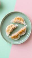 Delicately sliced cabbage and pork dumplings served on a mint green plate against a pastel backdrop photo