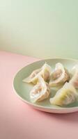 Delicately sliced cabbage and pork dumplings served on a pale green plate with a pastel pink background photo