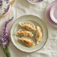 Artfully arranged cabbage and pork dumplings served on a vintage plate with lavender accents on a delicate table setting photo