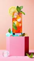 Turmeric iced tea served in a transparent glass with lemon and mint on a vibrant pink background photo