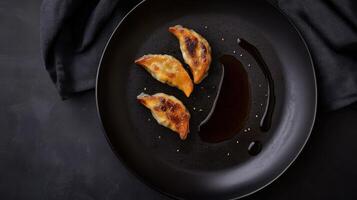Delicious dumplings served with soy sauce on a black plate for an appetizing presentation photo