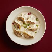 Dumplings served in creamy sauce with green onions on an elegant plate photo