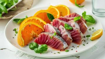 Deliciously fresh tuna sashimi garnished with vibrant orange slices and leafy basil on a white plate photo