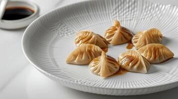 Crescent-shaped dumplings served on an elegant white plate with dipping sauce on the side at a modern dining table photo