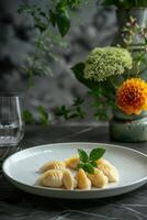 Delicate crescent-shaped dumplings presented on a white plate with fresh mint leaf amid a stylish dining setup photo