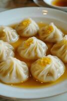 Delicately arranged soup dumplings served in a fine broth on a white plate at a cozy dining setting photo