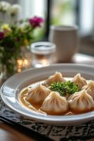 Delicately arranged soup with dumplings on a white plate in a cozy dining setting photo