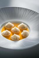 Delicate soup served in a white plate with elegant arrangement of dumplings in a modern dining setting photo