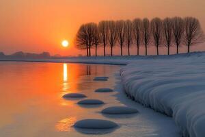Winter Sunset Over Snowy Riverbank with Trees Reflecting on Water photo
