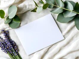 Blank greeting card for wedding invitation mockup surrounded by lavender and eucalyptus leaves on a soft fabric background, perfect for personalized messages. photo