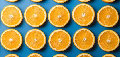 Fresh orange slices arranged in a neat grid pattern atop a vibrant blue background during a sunny afternoon photo