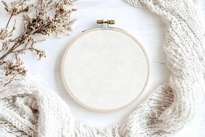 Soft texture of a knitted blanket and an empty embroidery hoop on a wooden surface with delicate dried flowers photo