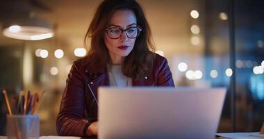 Focused woman working late on laptop in office. photo