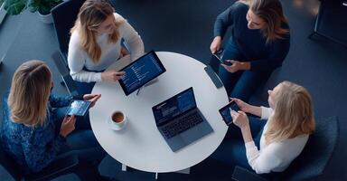 Four women collaborating on a project using tablets and laptops. photo