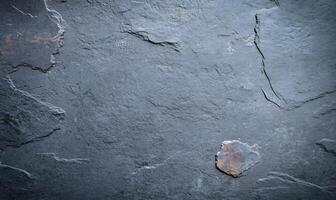 Dark gray slate stone slab surface texture with natural patterns and a small rusty spot. photo