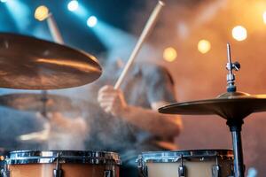 Drummer playing drums on stage with lights and smoke. photo