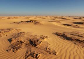 Vast Desert Landscape Beneath a Clear Sky at Golden Hour Time Photography in Natural Environment With Sand Dunes And Rocks and Texture and View from a Distance Under Dry and Empty Desert Space. With photo