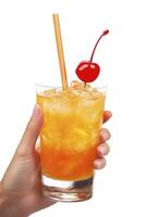 A hand holding an orange cocktail with ice and a cherry on top, with the straw extending upwards into it. The background is white. photo