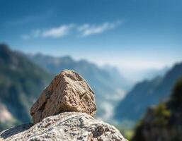 A rock sitting on top of a mountain with a blue sky in the background photo