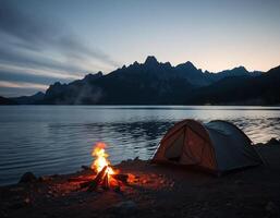 A tent is set up on the shore of a lake with mountains in the background photo