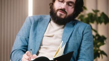 Close-up of a self-confident psychologist in glasses taking notes during a conversation with a patient. Concept of professional psychological support in solving personal problems. video