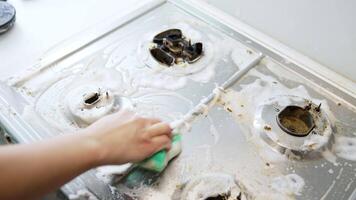 Scrubbing stove with soap. A person is scrubbing a dirty kitchen stove with soap, removing grime and grease. video
