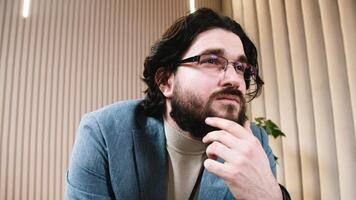 Close-up of a confident, bearded therapist wearing glasses during a consultation. Concept of professional psychological support aimed at solving personal issues and enhancing life quality. video