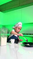 Young chef preps in kitchen. A young child in a chef hat measures ingredients into a blender, smiling while cooking in a brightly lit kitchen. video